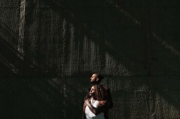 Elopement couple in harsh light with groom wrapped around bride