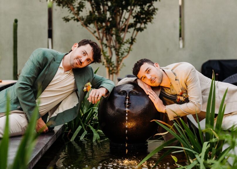 Two grooms leaning on fountain